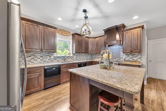 kitchen with sink, custom exhaust hood, stainless steel fridge, black dishwasher, and pendant lighting