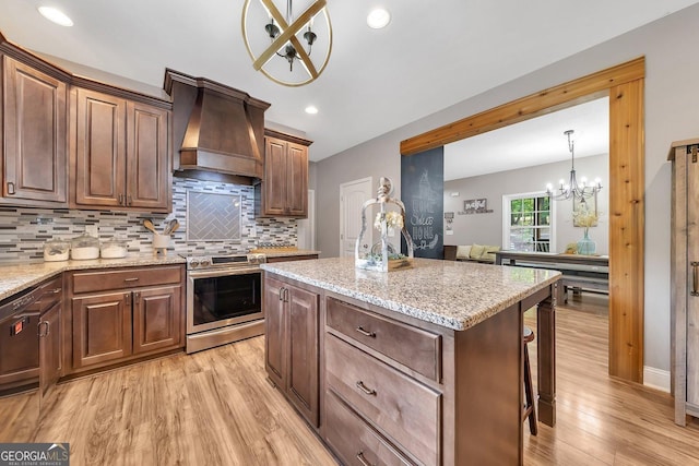 kitchen with electric range, tasteful backsplash, light hardwood / wood-style floors, custom range hood, and a kitchen island