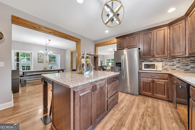 kitchen featuring tasteful backsplash, a center island, stainless steel fridge with ice dispenser, pendant lighting, and light stone countertops