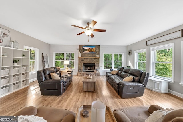 living room with ceiling fan, a fireplace, and light hardwood / wood-style floors