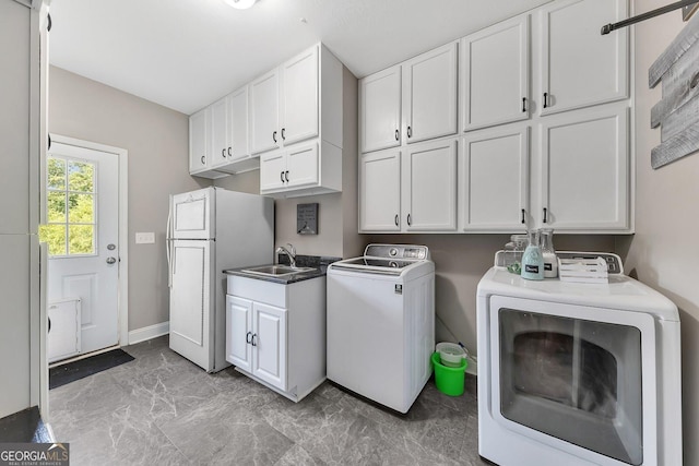 laundry room with sink, washing machine and dryer, and cabinets