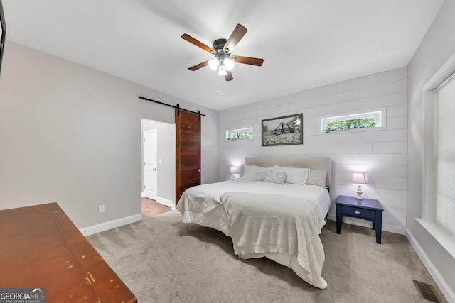 carpeted bedroom with ceiling fan and a barn door