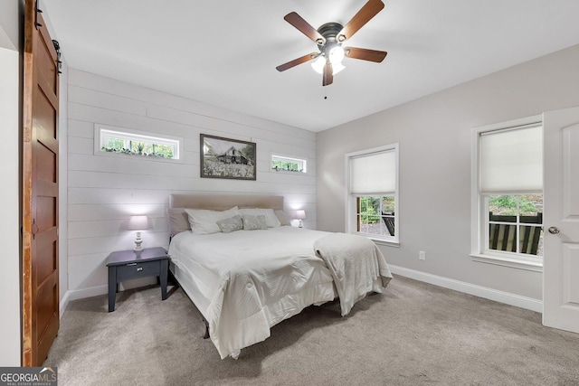 carpeted bedroom with a barn door and ceiling fan