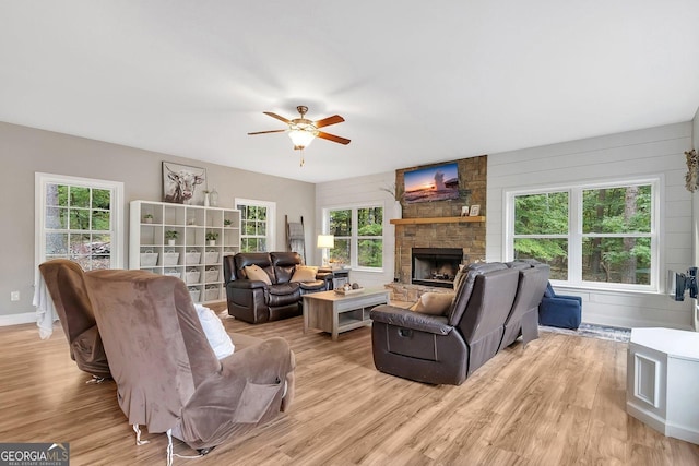 living room featuring a stone fireplace, plenty of natural light, and light wood-type flooring