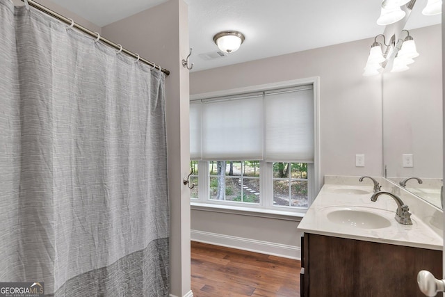 bathroom with wood-type flooring, vanity, and an inviting chandelier