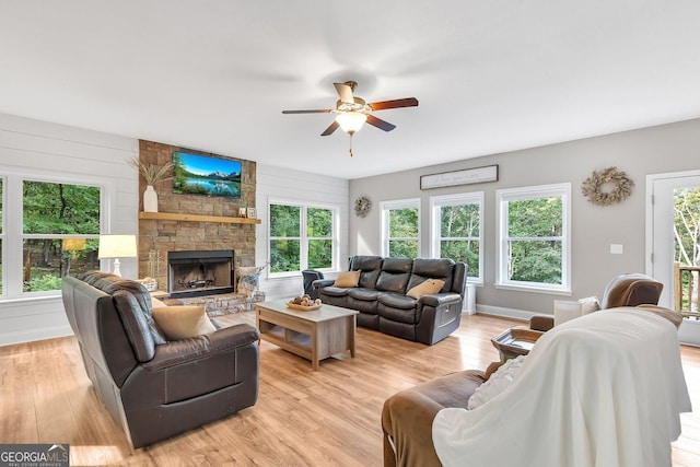 living room featuring ceiling fan, a fireplace, and light hardwood / wood-style floors