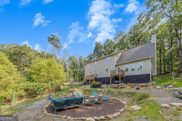 back of house featuring a fire pit and a deck