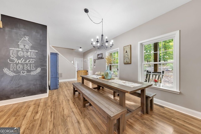 dining space with light hardwood / wood-style floors and a chandelier