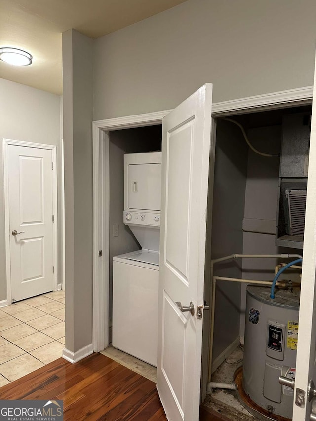 washroom with hardwood / wood-style flooring, electric water heater, and stacked washer / dryer