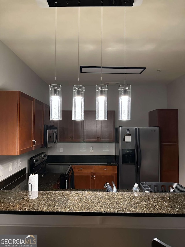 kitchen with hanging light fixtures, stainless steel appliances, and dark stone counters