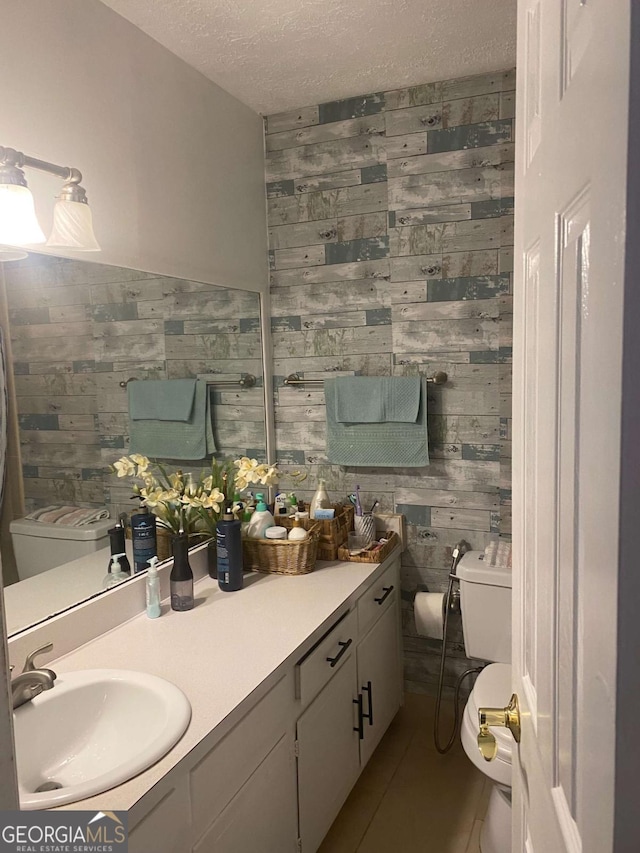 bathroom with vanity, wooden walls, a textured ceiling, and toilet