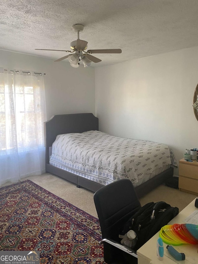 bedroom featuring ceiling fan, a textured ceiling, and carpet