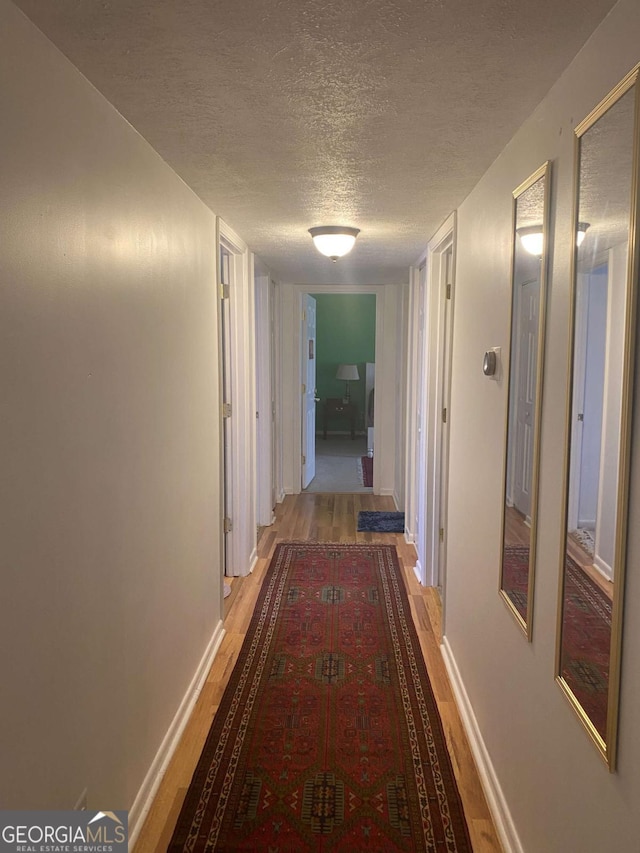 hallway featuring light hardwood / wood-style flooring and a textured ceiling