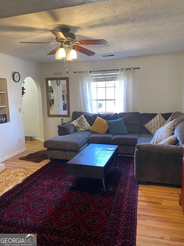 living room with ceiling fan, light hardwood / wood-style flooring, and a textured ceiling