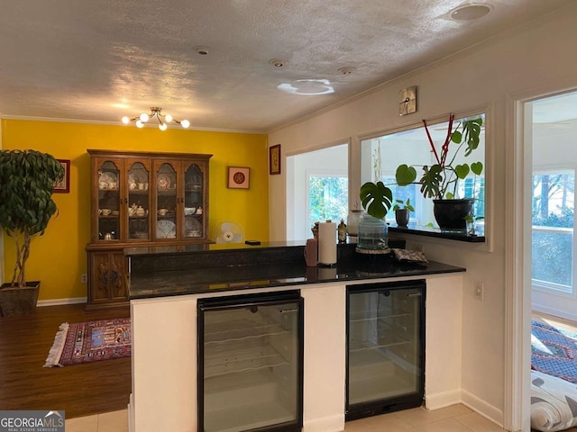 bar featuring wine cooler, crown molding, and a textured ceiling