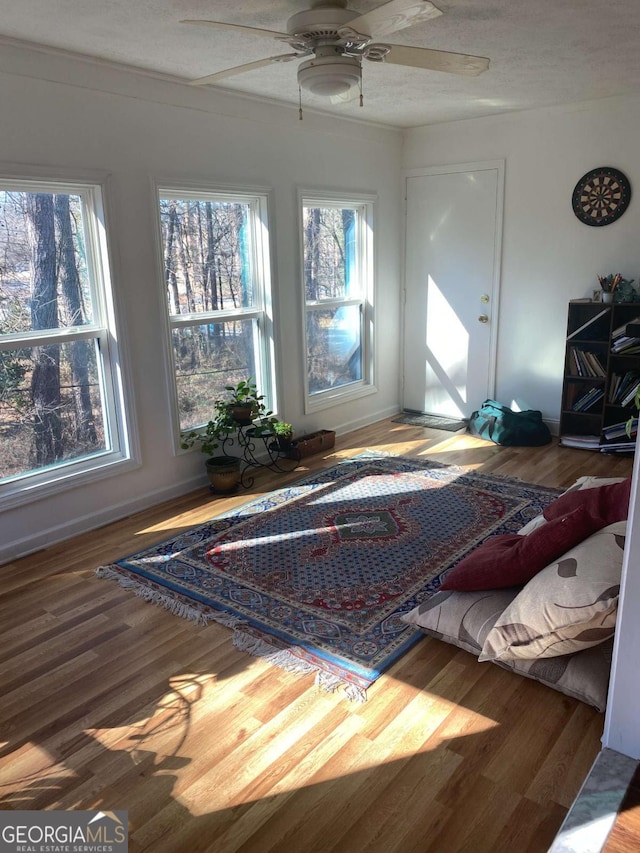 interior space with ceiling fan, hardwood / wood-style floors, multiple windows, and a textured ceiling