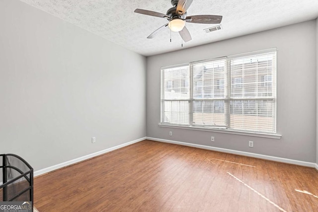 spare room featuring ceiling fan, wood-type flooring, and a textured ceiling