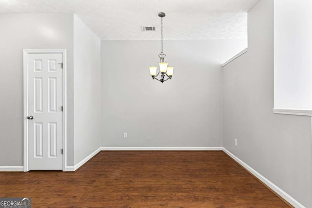 empty room with wood-type flooring, a textured ceiling, and a chandelier