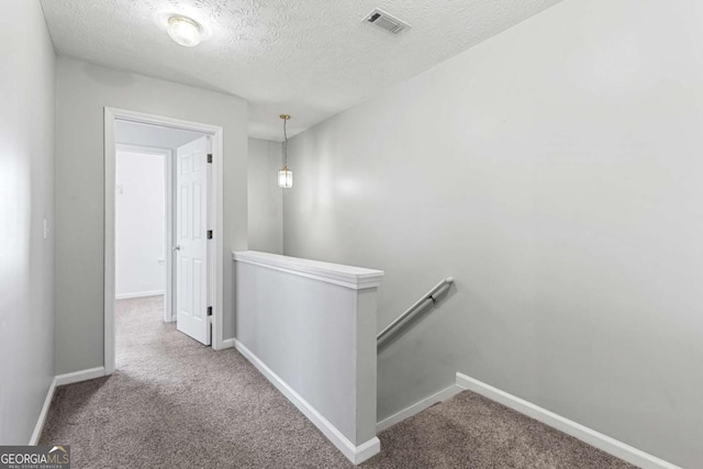 hall featuring a textured ceiling and carpet