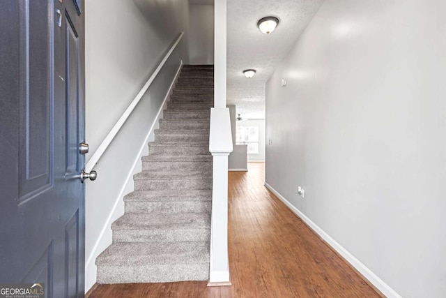 stairs featuring wood-type flooring and a textured ceiling