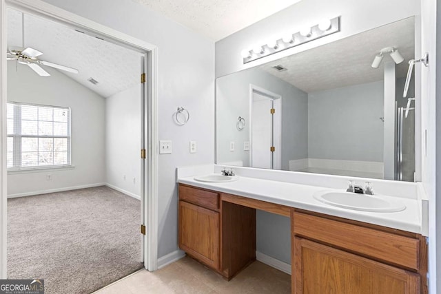 bathroom featuring lofted ceiling, ceiling fan, vanity, a textured ceiling, and tile patterned floors