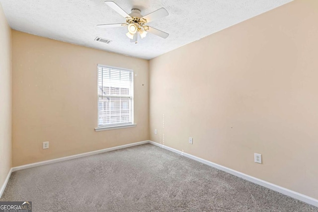 carpeted empty room featuring ceiling fan and a textured ceiling