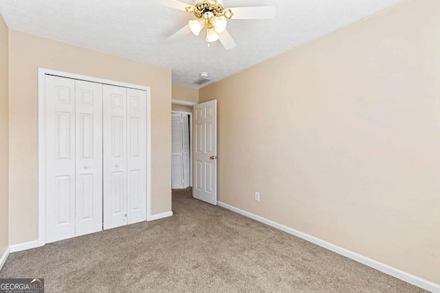 unfurnished bedroom with ceiling fan, carpet flooring, a textured ceiling, and a closet