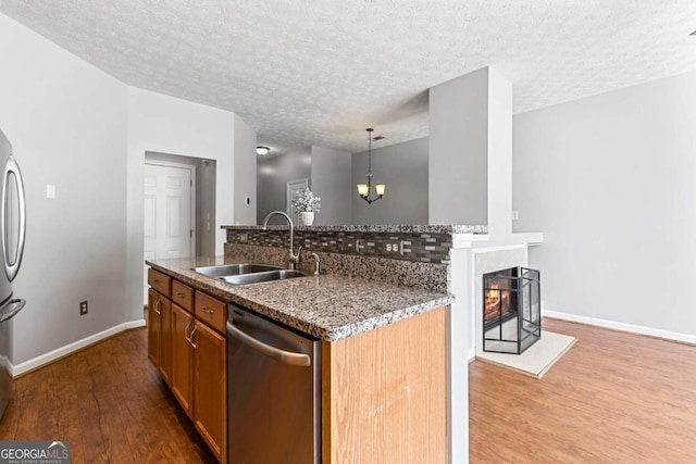 kitchen with pendant lighting, sink, dishwasher, wood-type flooring, and a center island with sink