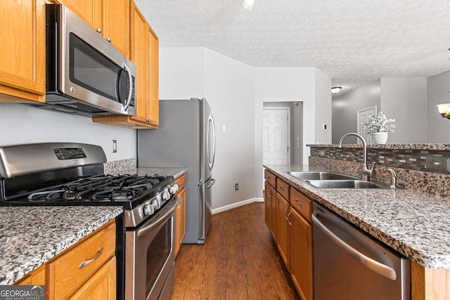 kitchen with sink, a textured ceiling, dark hardwood / wood-style flooring, stainless steel appliances, and light stone countertops