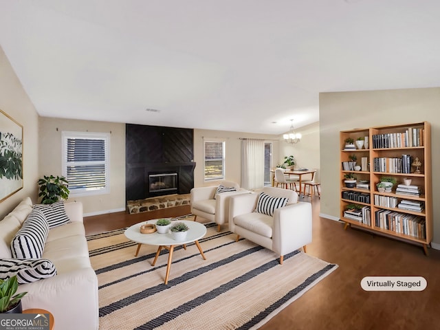 living room featuring hardwood / wood-style flooring, a large fireplace, a chandelier, and vaulted ceiling