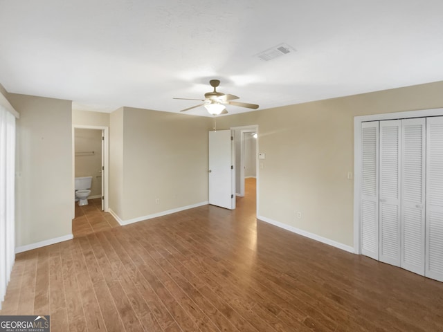 unfurnished bedroom featuring hardwood / wood-style flooring, connected bathroom, ceiling fan, and a closet