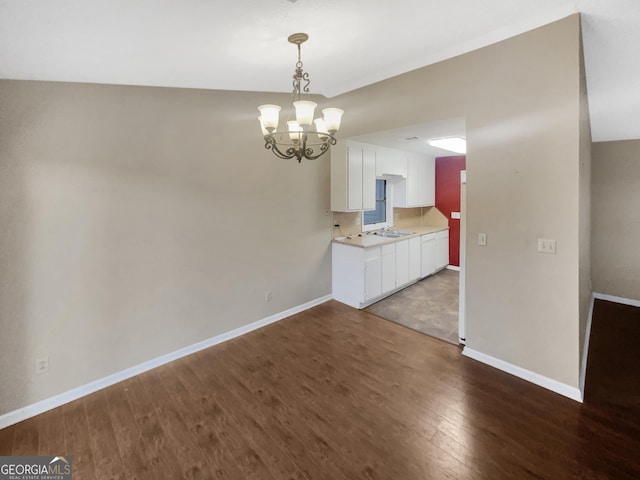 unfurnished dining area featuring sink, hardwood / wood-style flooring, and a chandelier