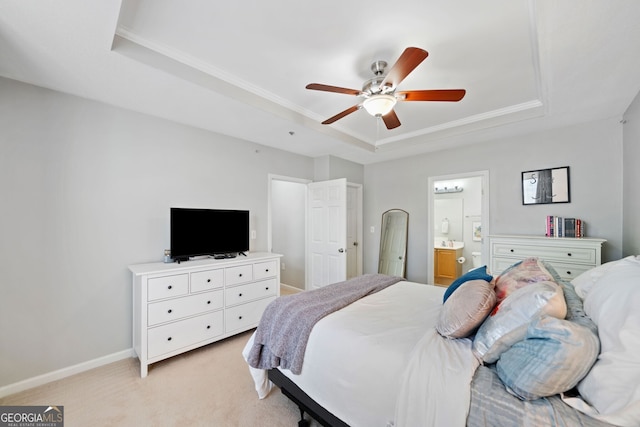 bedroom featuring connected bathroom, light colored carpet, ceiling fan, and a tray ceiling