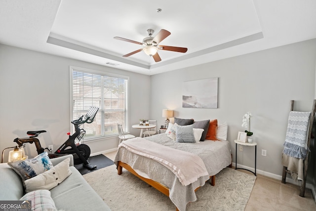 carpeted bedroom featuring ceiling fan and a tray ceiling