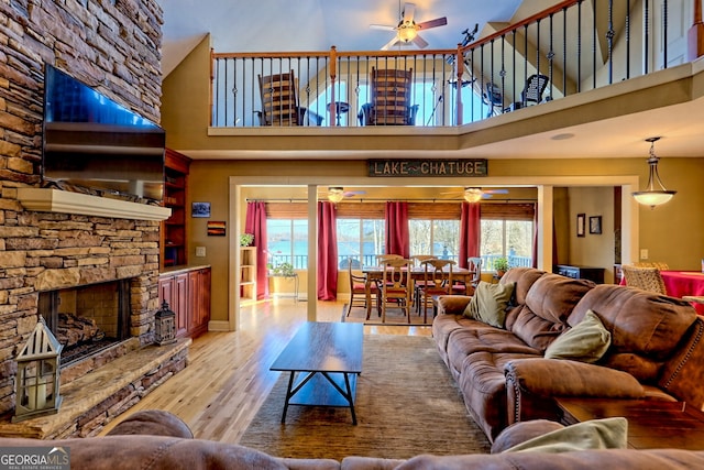 living room featuring ceiling fan, a wealth of natural light, a fireplace, and light hardwood / wood-style flooring