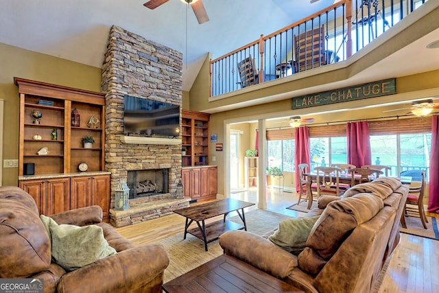 living room with a fireplace, light hardwood / wood-style flooring, high vaulted ceiling, and ceiling fan