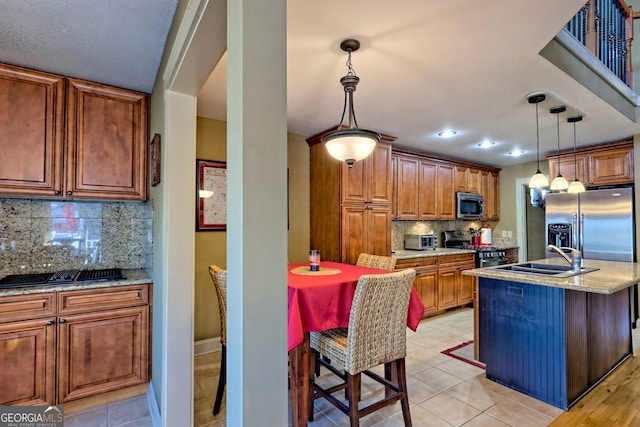 kitchen with appliances with stainless steel finishes, a kitchen island with sink, sink, and a kitchen breakfast bar