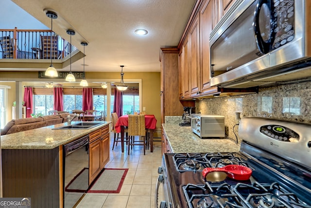 kitchen with light tile patterned flooring, sink, hanging light fixtures, an island with sink, and stainless steel appliances