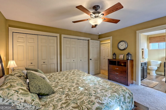 carpeted bedroom featuring multiple closets, ceiling fan, and connected bathroom