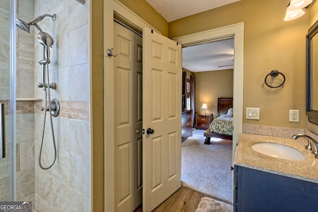 bathroom featuring hardwood / wood-style flooring, vanity, and a tile shower