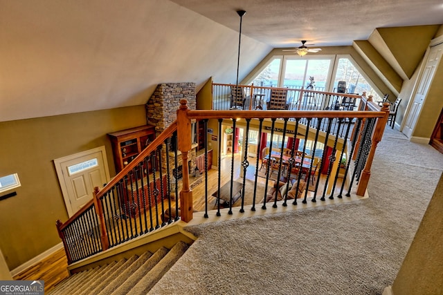 stairs with ceiling fan, carpet floors, and vaulted ceiling