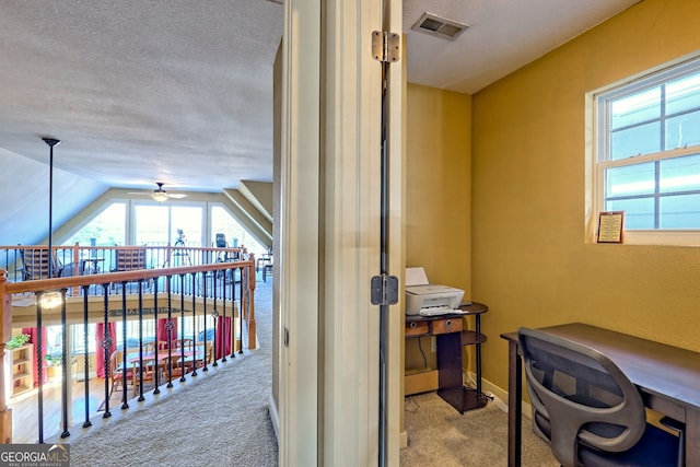 home office with a healthy amount of sunlight, light carpet, a textured ceiling, and ceiling fan