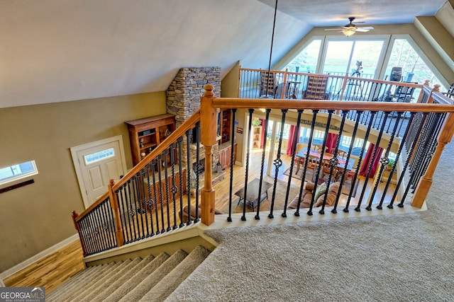 stairs featuring lofted ceiling, wood-type flooring, and ceiling fan