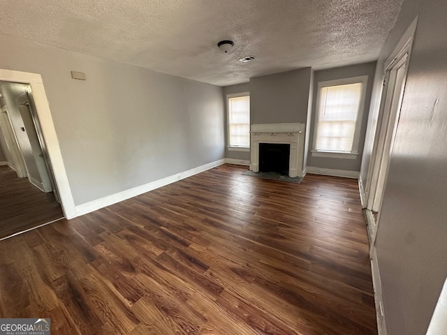 unfurnished living room featuring dark wood-type flooring and a textured ceiling