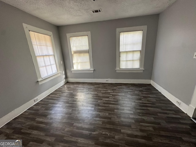 unfurnished room with a textured ceiling and dark hardwood / wood-style flooring