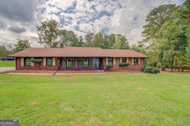 single story home with a porch, brick siding, a chimney, and a front lawn