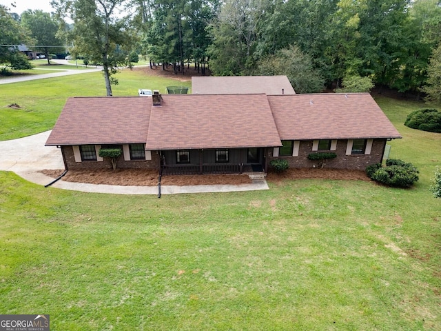 view of front of house featuring brick siding, roof with shingles, and a front yard