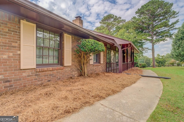 view of home's exterior featuring brick siding, a chimney, and a lawn