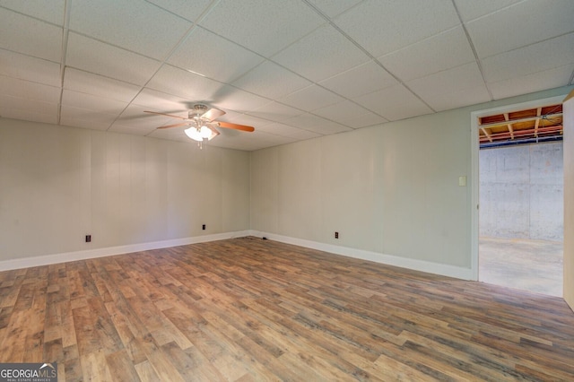 basement with a paneled ceiling, baseboards, and wood finished floors