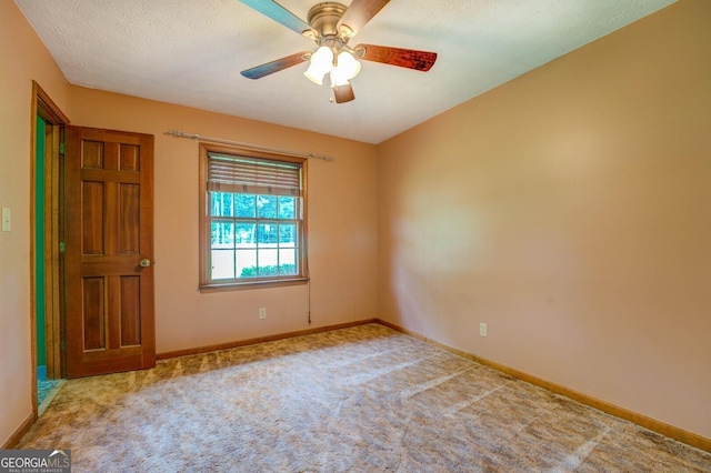 carpeted empty room with ceiling fan, a textured ceiling, and baseboards